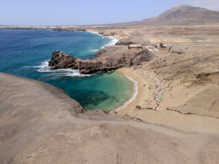 Aerial view of Playa de Papagayo in Lanzarote, Canary Islands, featuring a golden sandy beach, turquoise bay, and arid volcanic landscape.
