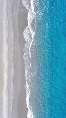Beautiful Sandy Beach Meeting Clear Blue Ocean Waves During a Sunny Day in a Coastal Location