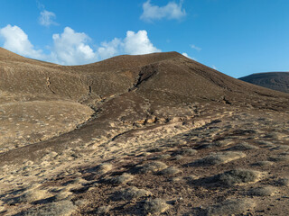 Aerial view of a secluded sandy beach on La Graciosa island with turquoise ocean water and rugged volcanic cliffs.  
