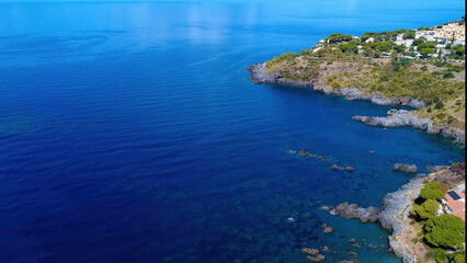 Clear Blue Waters and Rocky Coastline Near a Quaint Hilltop Village in Summer Sunshine. Scalea, Calabria, Italy