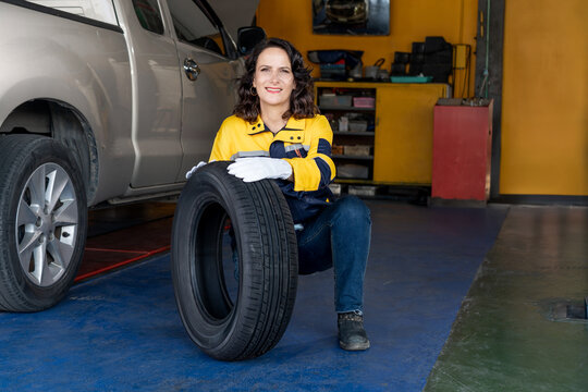 mechanic woman worker checking car tires in auto repair shop store service. caucasian female worker maintenance examining wheel tire at garage