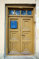 Weathered Yellow Wooden Door with Blue Mailbox in a Historic Building