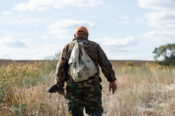 A hunter with a gun in camouflage clothing. A gentleman with a gun, medium shot, unrecognizable.