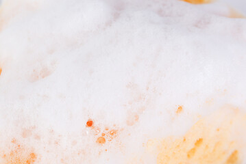 Cleaning concept with dish sponge and soap suds, backdrop.