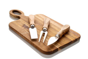 Cheese knives and fork with kitchen wooden board on white background, close-up.