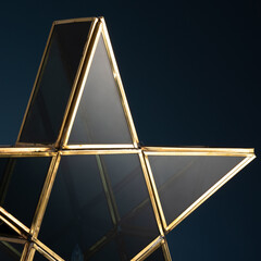 Elegant geometric star lantern with gold metal frame and tinted glass panels, styled against a dark backdrop. Perfect for festive decor, ambient lighting, or modern home interiors