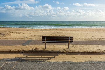 East Cliff Beach, Bournemouth, UK - October 24th 2025: Wooden public bench on the empty sandy beach facing the sea.