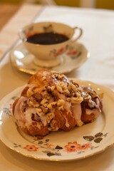 Traditional Polish Saint Martin’s croissant (rogal świętomarciński) served on elegant vintage porcelain with a cup of coffee in the background.