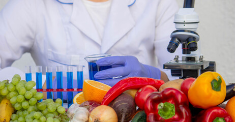 Chemical analysis of fruits and vegetables: scientist working with a beaker next to produce