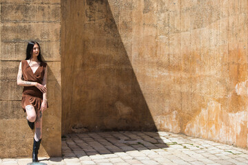 Latin woman, young and pretty brunette with tattoos on her arms and legs, wearing a brown dress and...