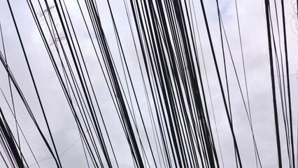 Dense network of power wires fills urban setting skyline, network intertwining overhead, network...