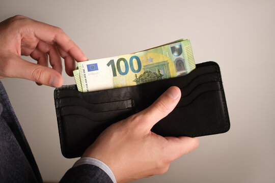Selective focus of man's hands fold euro banknotes into a wallet