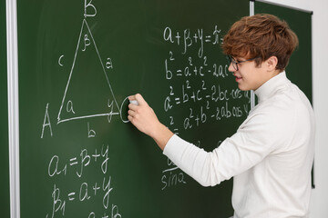 Back to school. Student doing math on chalkboard indoors