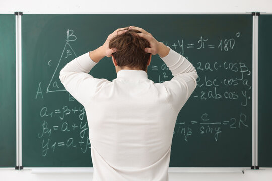 Back to school. Student near chalkboard with math assignment indoors