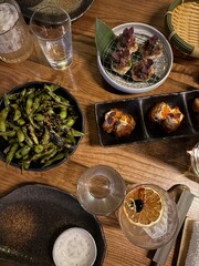 Modern Japanese Fusion Dinner with Edamame and Appetizers; a stylish Japanese fusion dinner table featuring grilled edamame with sesame, crispy appetizers topped with fish roe, and beef tartare bites 