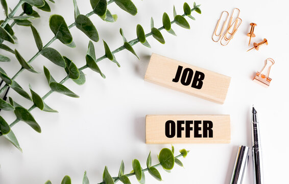 JOB OFFER text on a wooden blocks with eucalyptus, pens and office supplies on white background.