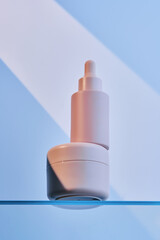 A bottle of serum and cream on the glass shelf of the bathroom.