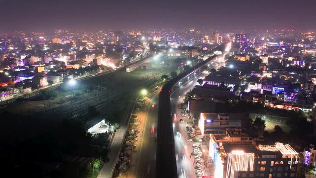 Aerial drone hyper time lapse showing Indian city on diwali night with traffic passing by decorated buildings and fireworks on the horizon showing the celebration of this hindu festival of light