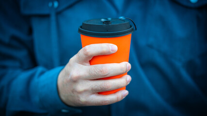 Hand Holding Bright Orange Takeaway Coffee Cup with Black Lid