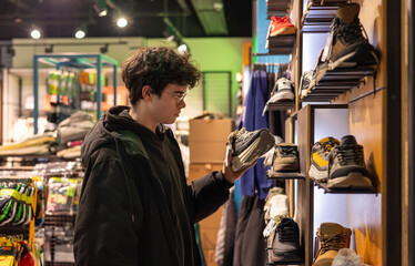 Teen boy in clothing and footwear store selecting sneakers, browsing youth fashion shoes, retail shopping experience in mall, generation Z style choice