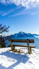 Fototapeta premium Wooden bench on snowy mountaintop under a vibrant blue sky