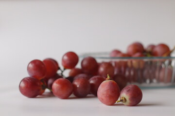 Red table grapes in a clear glass bowl, featuring Red Globe, Crimson Seedless, or Flame Seedless