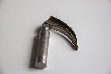 Laryngoscope lying on a white table. Horizontal shot.