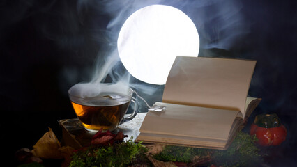 Eine dampfende Teetasse neben einem offenen Buch. Im Hintergrund der Vollmond. 