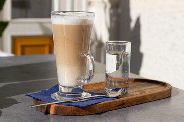 Hot coffee is served in tall glass with water in a resturant for breakfast. V1
