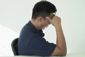 An asian businessman is suffering from headache, tension from forehead and getting stress and depression during working, massaging his head, employee life office stress and office syndrome concept.	
