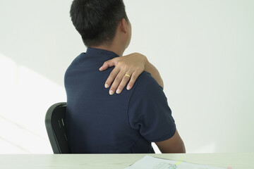 An asian businessman having tensed muscles fatigued, neck, shoulder, back pain during work long time in office, due to fibromyalgia, rheumatism, scapular pain, office syndrome and ergonomic concept.