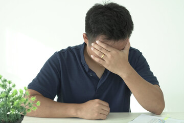 An asian businessman is suffering from headache, tension from forehead and getting stress and depression during working, massaging his head, employee life office stress and office syndrome concept.	
