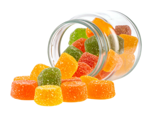 Colorful fruit gummies spill out of a clear, angled jar against a black background