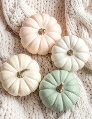 Four mini pumpkins rest atop a soft, cream-colored knitted blanket