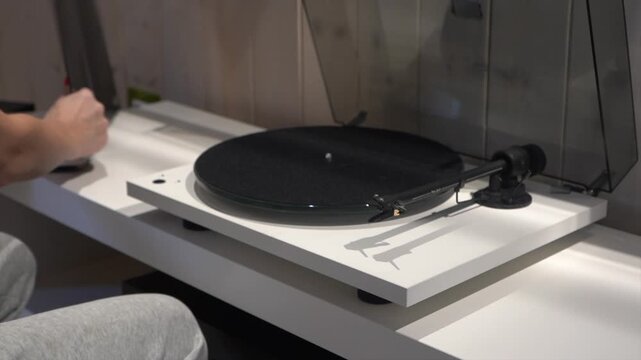 A girl listens to music on a vinyl record player. A young woman places a vinyl record on the player.