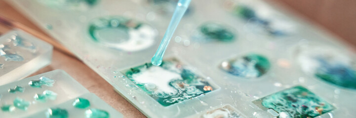 Close-up of colored resin art creation with liquid details in silicone mold for crafting...