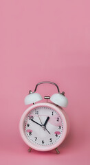 Round alarm clock on a pink background, copy space for text