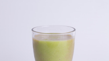 Close up of Fresh Avocado Juice Isolated on White Background with Copy Space. Healthy green smoothie drink for diet, detox, and summer refreshment promotion.
