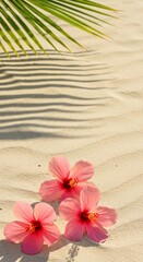 Fototapeta premium Hibiscus flowers rest on sun-kissed sand, shadows from palm leaves dance above. A serene tropical beach scene.