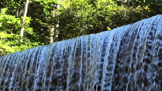Wasserfall &uuml;ber die Staumauer im Wald in den Bergen, Wildbach