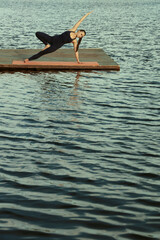 front view of 1 one alone fit female lady woman girl in sportswear standing on pier coast practicing yoga near waving sea Vertical Format Empty copy space for inscription