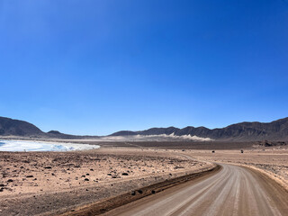 Beautiful scenic landscape view with beach on side and dirt road going through  National Parc Pan de Azúcar in Chile. This natural area showcases unique desert flora, dramatic cliffs, beaches.