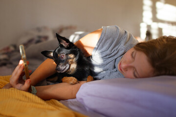 Morning moment &mdash; preteen girl with her chihuahua dog in bed using smartphone