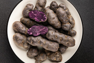 Purple potatoes raw fruit blue potatoe vegetable dish fresh gourmet food background on the table rustic food top view copy space keto and paleo diet vegan and vegetarian food