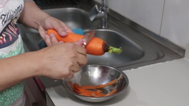 Quitando la c&aacute;scara a una zanahoria con un pelador de zanahoria en la cocina, ambiente una cocina peque&ntilde;a