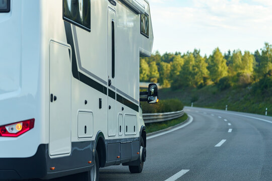 Motorhome traveling along a winding road in a scenic landscape at sunset