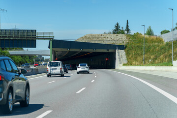 Cars driving towards a tunnel on a sunny day in a modern urban setting