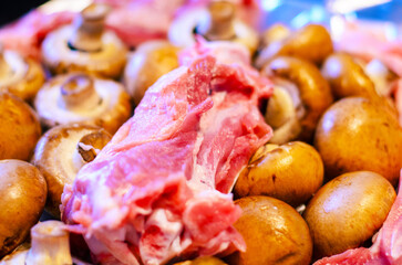 Fresh raw pork meat and mushrooms ready for cooking, close-up shot