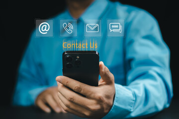 Business communication concept with contact us icons on digital interface. Professional holding transparent tablet with email, chat, and phone symbols for customer service and support solutions.