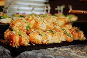 Golden croissant sandwiches with crispy onions and sesame seeds on dark serving tray